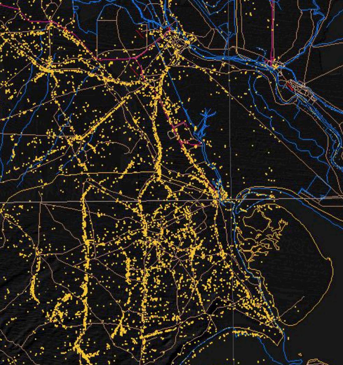 Dark-themed geospatial map of a metropolitan region with road network, rivers and reservoirs, overlaid with thousands of small yellow markers clustered along major transportation corridors indicating radar-detected moving ground targets