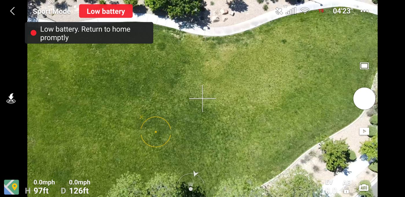 DJI Fly app over a park showing a red Low battery flag and a prompt to return home