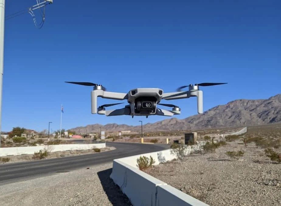 A DJI Mavic Mini hovering over a desert roadside
